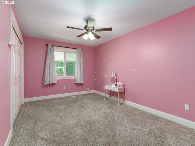 spare room with baseboards, ceiling fan, and carpet