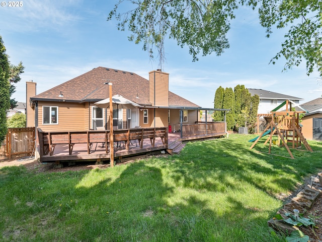 back of house with a fenced backyard, roof with shingles, a chimney, a playground, and a yard