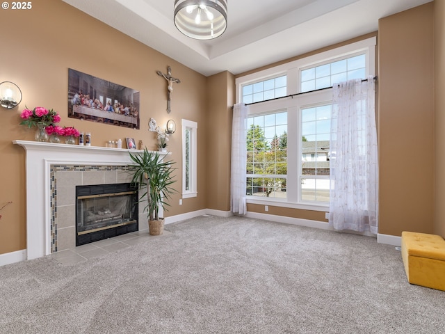 unfurnished living room featuring a tiled fireplace, carpet floors, and baseboards