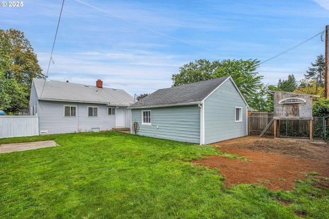 back of property with an outbuilding, a lawn, and fence