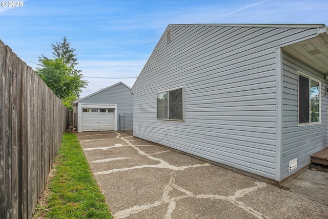 view of side of property with a garage, an outbuilding, concrete driveway, and fence