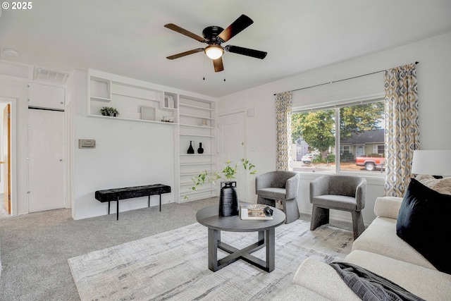 living area featuring ceiling fan, visible vents, and light colored carpet