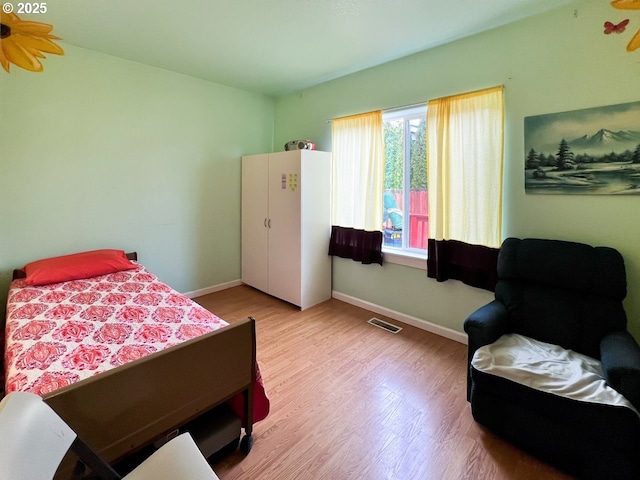 bedroom with light wood finished floors, baseboards, and visible vents