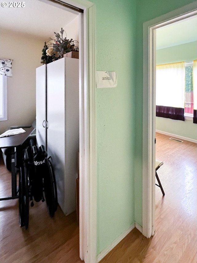 interior space with baseboards, visible vents, and light wood finished floors