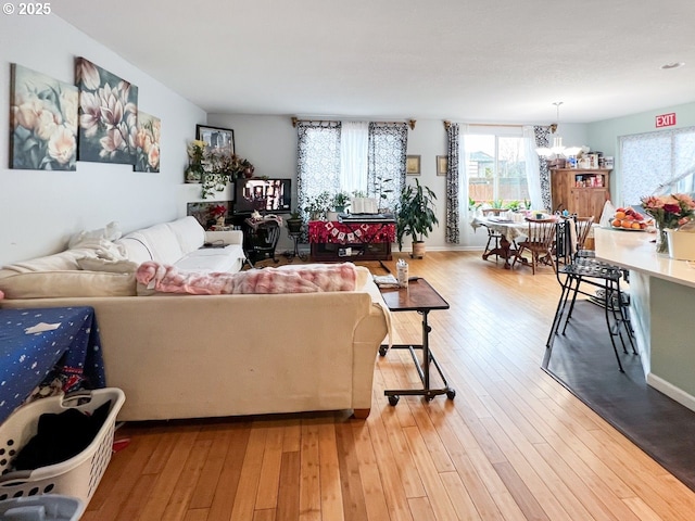 living room with a notable chandelier, light wood-style flooring, and baseboards