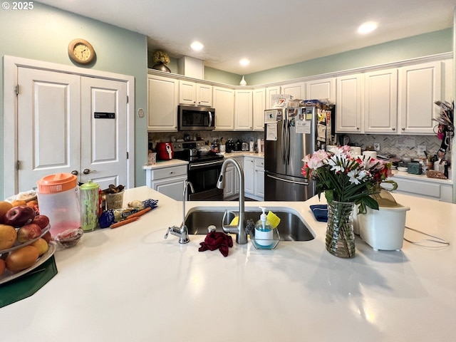 kitchen with a sink, white cabinets, light countertops, appliances with stainless steel finishes, and tasteful backsplash