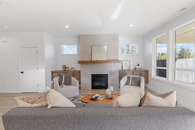 living room with a tiled fireplace and light hardwood / wood-style flooring