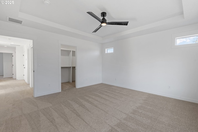 interior space with a raised ceiling and light carpet