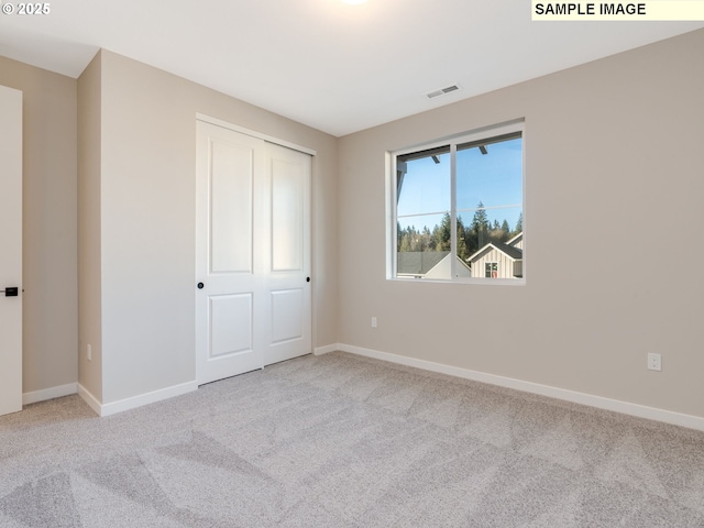 unfurnished bedroom featuring light carpet and a closet