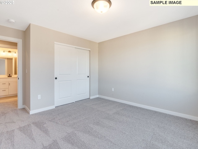 unfurnished bedroom featuring a closet, sink, and light carpet