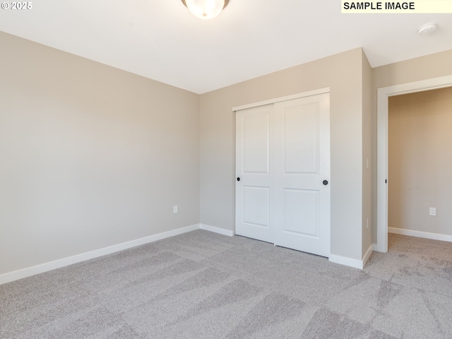 unfurnished bedroom featuring light colored carpet and a closet