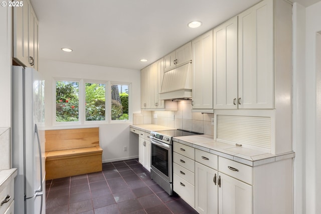 589 Ridgeway Rd, Lake Oswego, OR 97034 - kitchen with stainless steel electric range oven, freestanding refrigerator, custom range hood, tasteful backsplash, and dark tile patterned floors