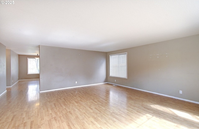 unfurnished room with baseboards and light wood-style floors