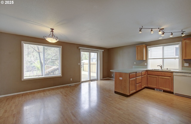 kitchen featuring white dishwasher, a peninsula, visible vents, light wood-style floors, and open floor plan