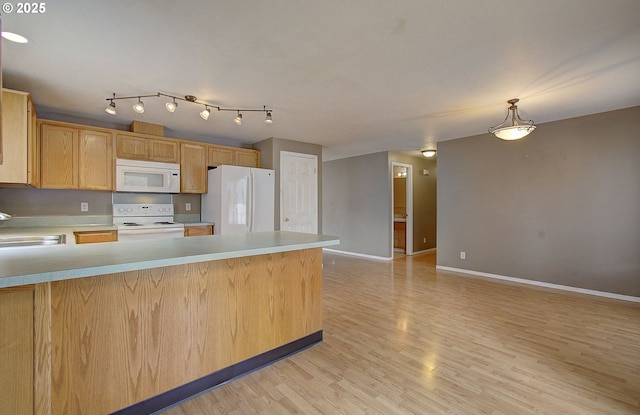 kitchen featuring white appliances, light countertops, a sink, and a peninsula