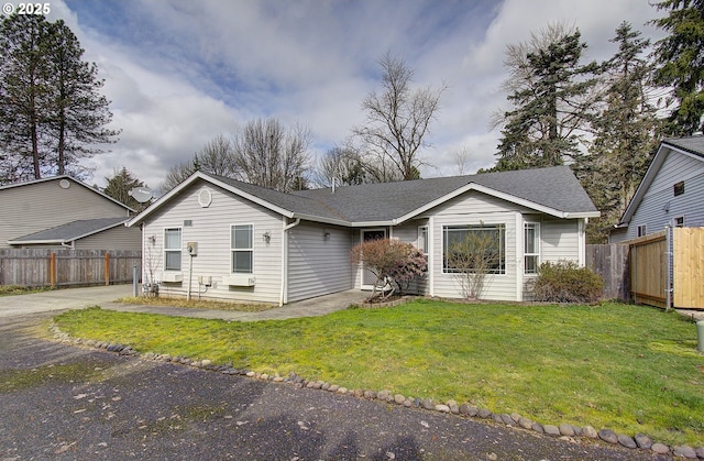 single story home featuring a shingled roof, a front yard, fence, and driveway