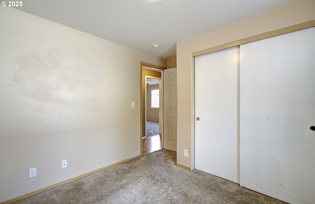 unfurnished bedroom featuring a closet, light colored carpet, and baseboards