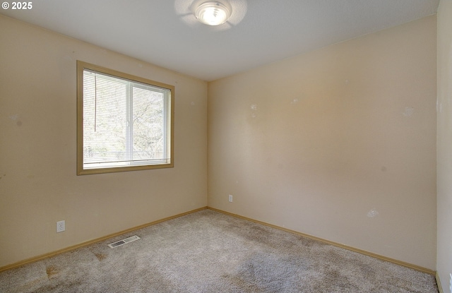 carpeted empty room featuring baseboards and visible vents