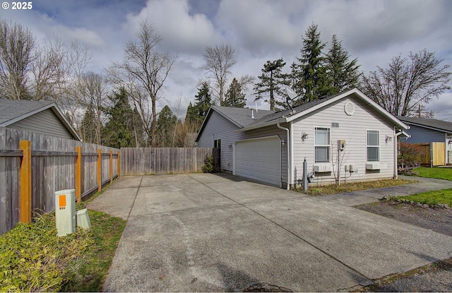 view of home's exterior featuring driveway, an attached garage, and fence