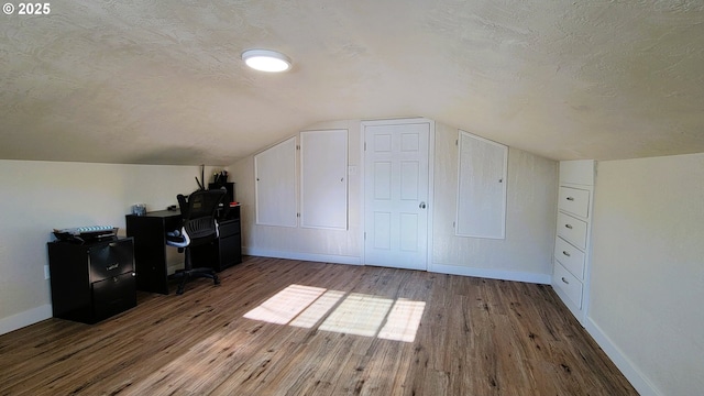 office area featuring a textured ceiling, vaulted ceiling, wood finished floors, and baseboards