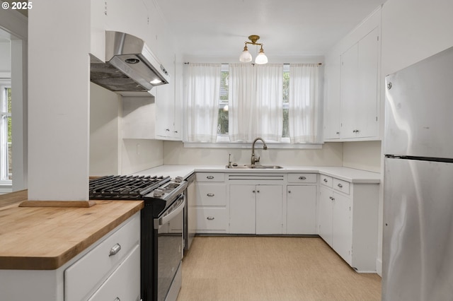 kitchen featuring a sink, extractor fan, freestanding refrigerator, gas stove, and wooden counters