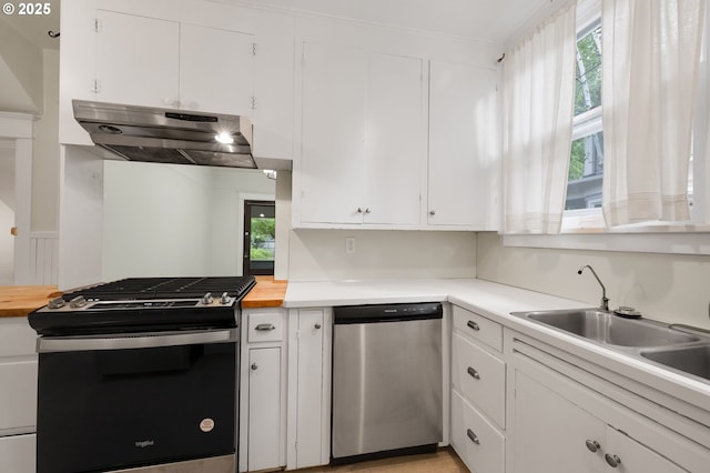 kitchen featuring under cabinet range hood, dishwasher, gas stove, a sink, and white cabinetry