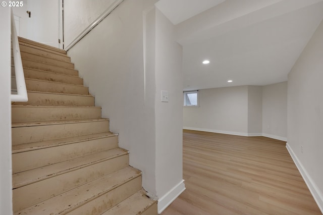 staircase with wood finished floors, baseboards, and recessed lighting