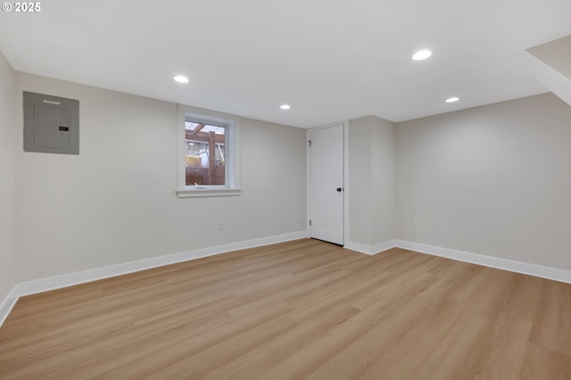 below grade area featuring electric panel, light wood-style flooring, baseboards, and recessed lighting