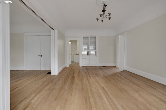 interior space featuring baseboards, light wood finished floors, and an inviting chandelier