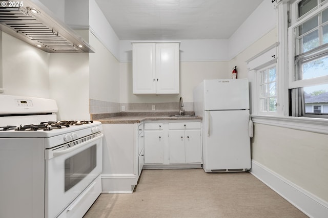 kitchen with a sink, white cabinets, white appliances, wall chimney range hood, and light carpet