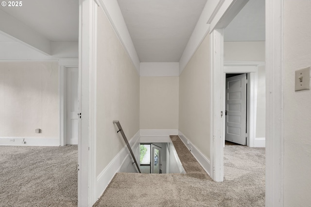 corridor with an upstairs landing, baseboards, and carpet floors