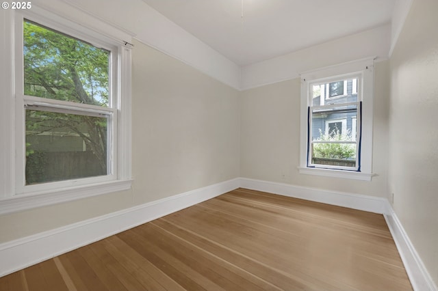spare room with baseboards and wood finished floors
