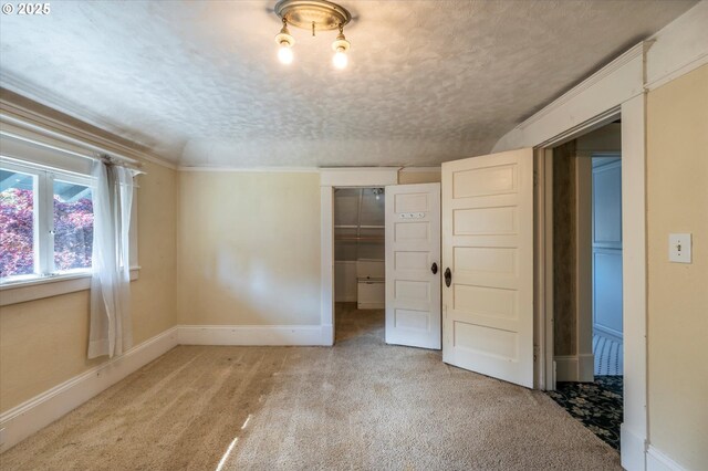 619 S 11th St, Coos Bay, OR 97420 - unfurnished bedroom featuring light colored carpet, baseboards, a closet, a walk in closet, and a textured ceiling
