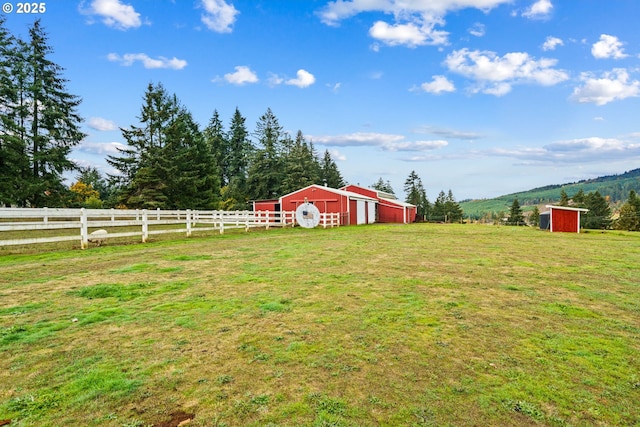 view of yard with a pole building, an outdoor structure, a view of rural / pastoral area, and a detached garage