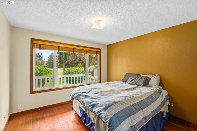 bedroom featuring hardwood / wood-style floors, a textured ceiling, and baseboards