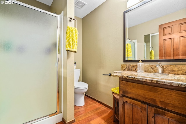 full bathroom featuring wood finished floors, toilet, a stall shower, baseboards, and vanity