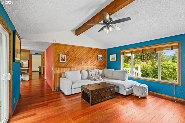 living room featuring wood walls, a textured ceiling, ceiling fan, and hardwood / wood-style flooring