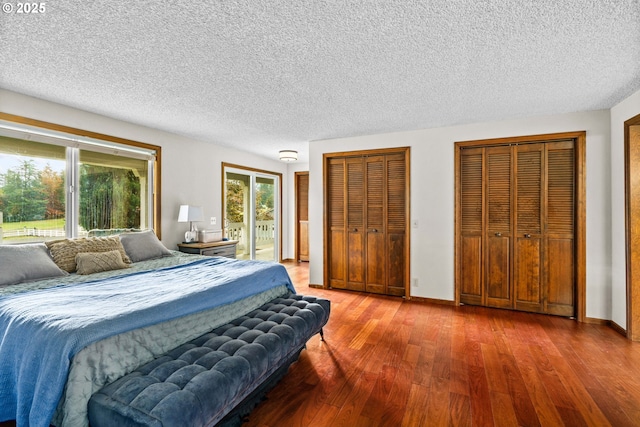 bedroom with wood finished floors, a textured ceiling, access to outside, multiple closets, and baseboards