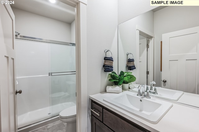 bathroom featuring toilet, vanity, tile patterned floors, and a shower with shower door