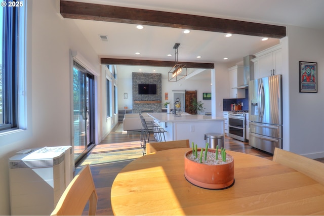 95660 Spirit Ridge Rd, Gold Beach, OR 97444 - dining space with dark wood finished floors, beamed ceiling, a stone fireplace, and recessed lighting