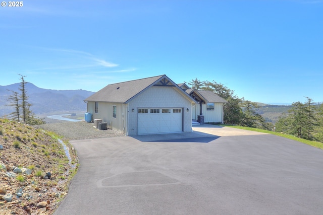 95660 Spirit Ridge Rd, Gold Beach, OR 97444 - view of front of home featuring asphalt driveway, a mountain view, an attached garage, and central air condition unit