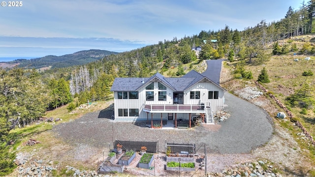 95660 Spirit Ridge Rd, Gold Beach, OR 97444 - back of house featuring board and batten siding, a wooded view, a deck with mountain view, stairway, and a garden