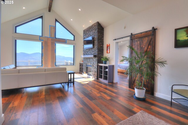 95660 Spirit Ridge Rd, Gold Beach, OR 97444 - living area with beam ceiling, high vaulted ceiling, wood finished floors, a barn door, and a fireplace