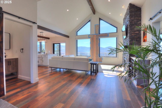 95660 Spirit Ridge Rd, Gold Beach, OR 97444 - living room featuring beam ceiling, dark wood-type flooring, plenty of natural light, high vaulted ceiling, and a barn door