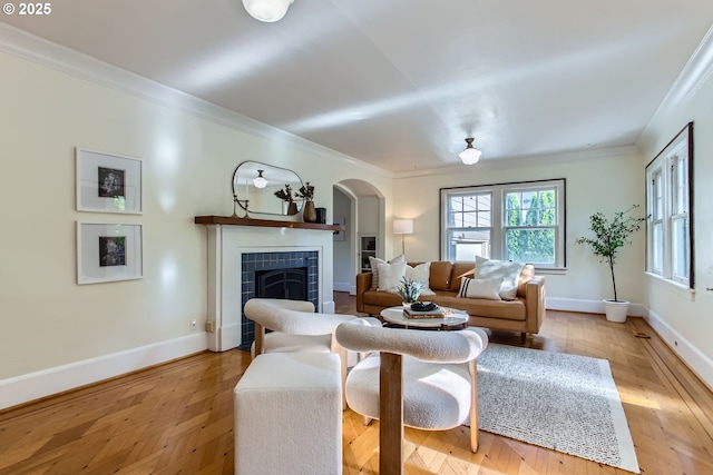 5536 N Delaware Ave, Portland, OR 97217 - living room featuring arched walkways, ornamental molding, a tile fireplace, baseboards, and light wood-style flooring