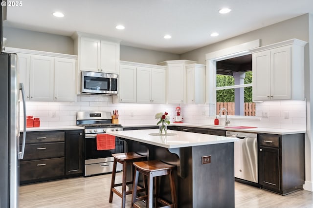 kitchen featuring stainless steel appliances, a sink, white cabinets, and recessed lighting