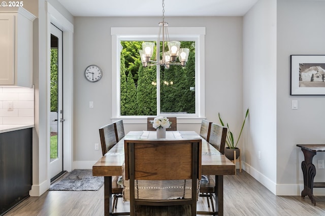 dining area with light wood-style flooring, a chandelier, and baseboards