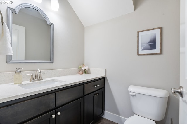 bathroom featuring toilet, vanity, vaulted ceiling, baseboards, and wood finished floors