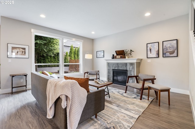 living room with a tiled fireplace, wood finished floors, baseboards, and recessed lighting