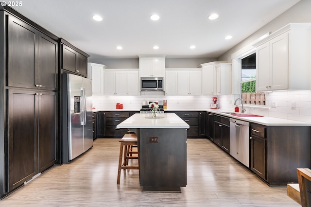 kitchen with appliances with stainless steel finishes, a sink, a center island, a breakfast bar, and tasteful backsplash